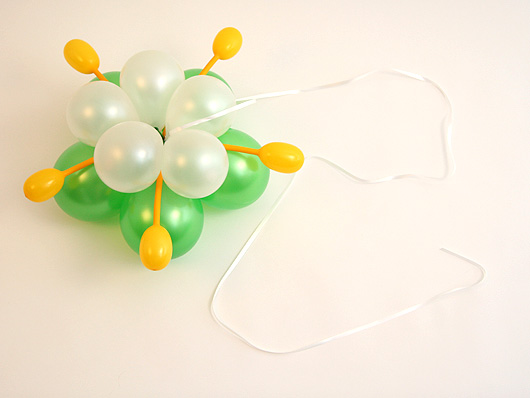  Привязываем белую ленту к основанию композиции из воздушных шариков 